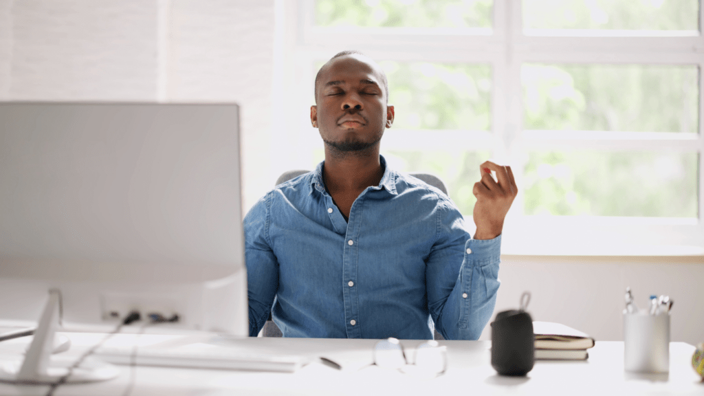 A man meditating in front of his computer.