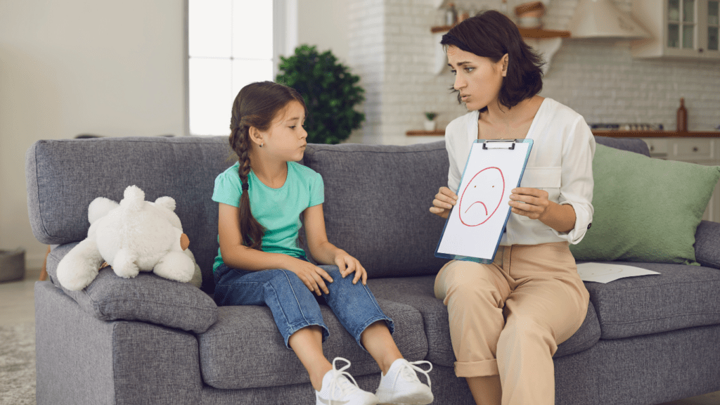 A person and a child sitting on a couch with a smiley face drawn on a piece of paper