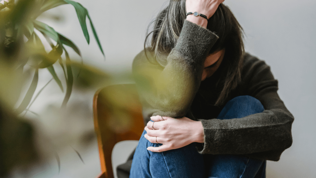 a person sitting on a chair with their head in their hands