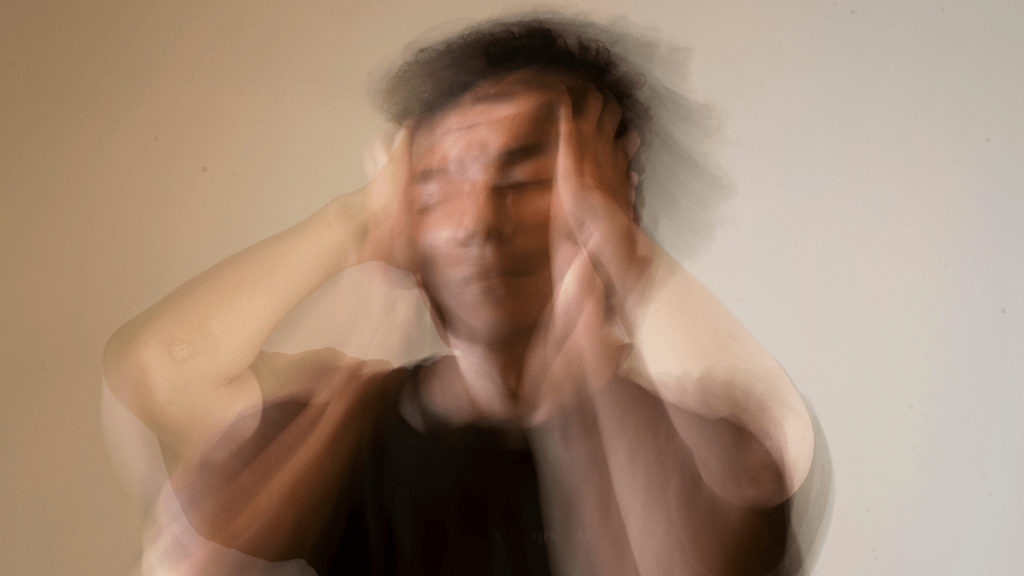 a blurry image of a person with their hands on their face