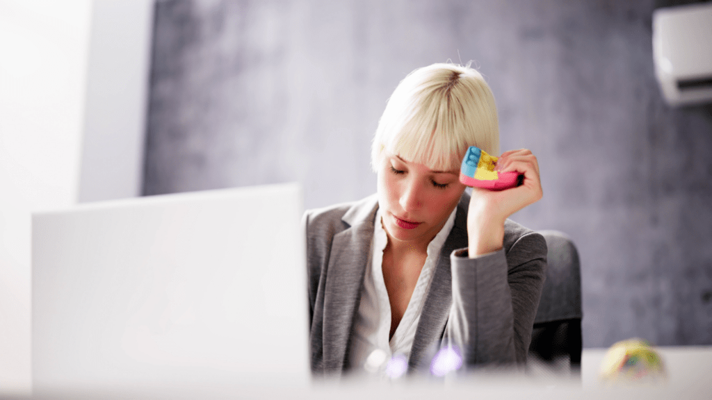 a person sitting in front of a laptop with their head in their hands