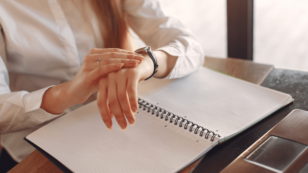 a person sitting at a desk with their hand on their wrist