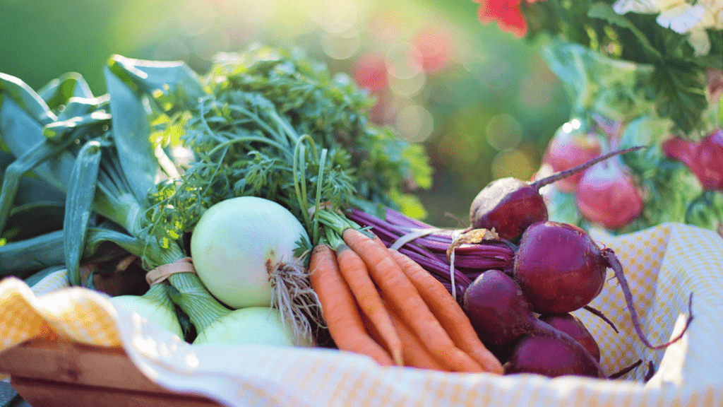 vegetables in a basket on a table with flowers in the background