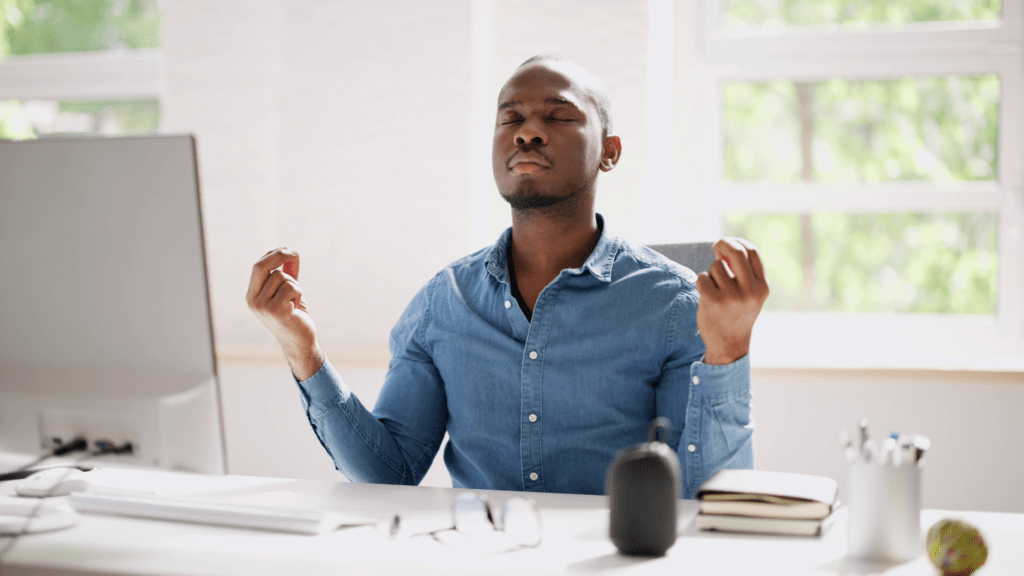 A man meditating in front of his computer.