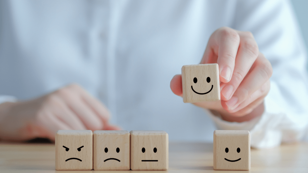 a person holding wooden blocks with smiley faces on them