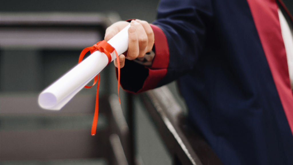 a person in a graduation gown is holding a diploma