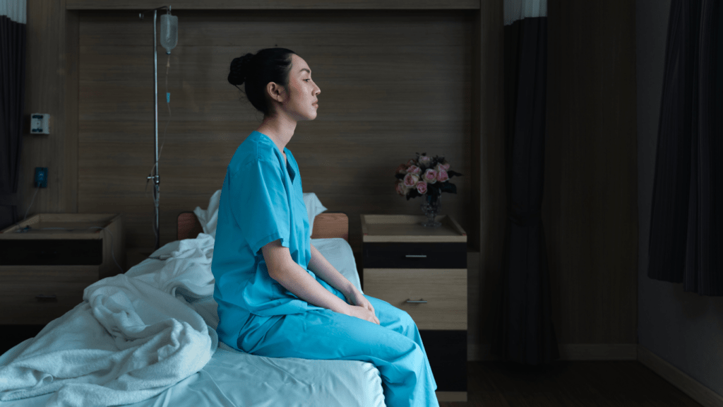 A person sitting on a bed in a hospital room