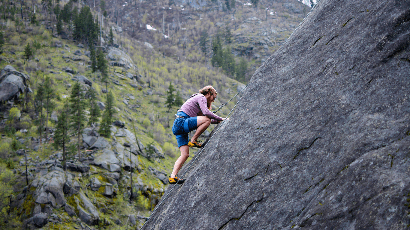 a person is climbing on the side of a mountain