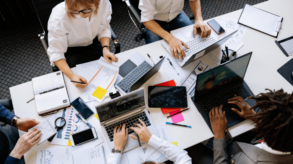 a group of people sitting around a conference table with laptops