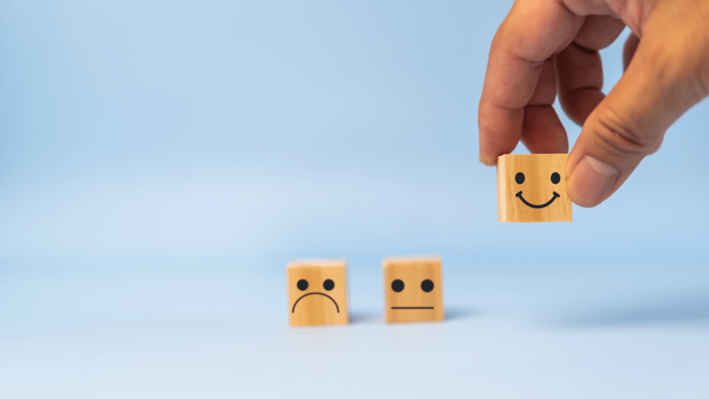 a person holding wooden blocks with smiley faces on them