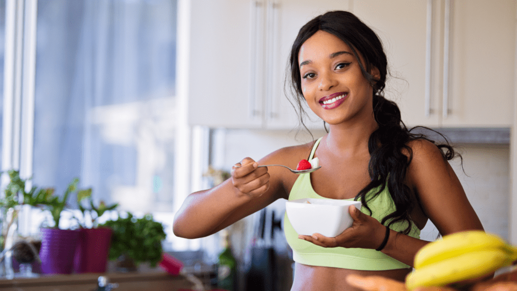 a person in a sports bra is preparing fruit and vegetables in the kitchen