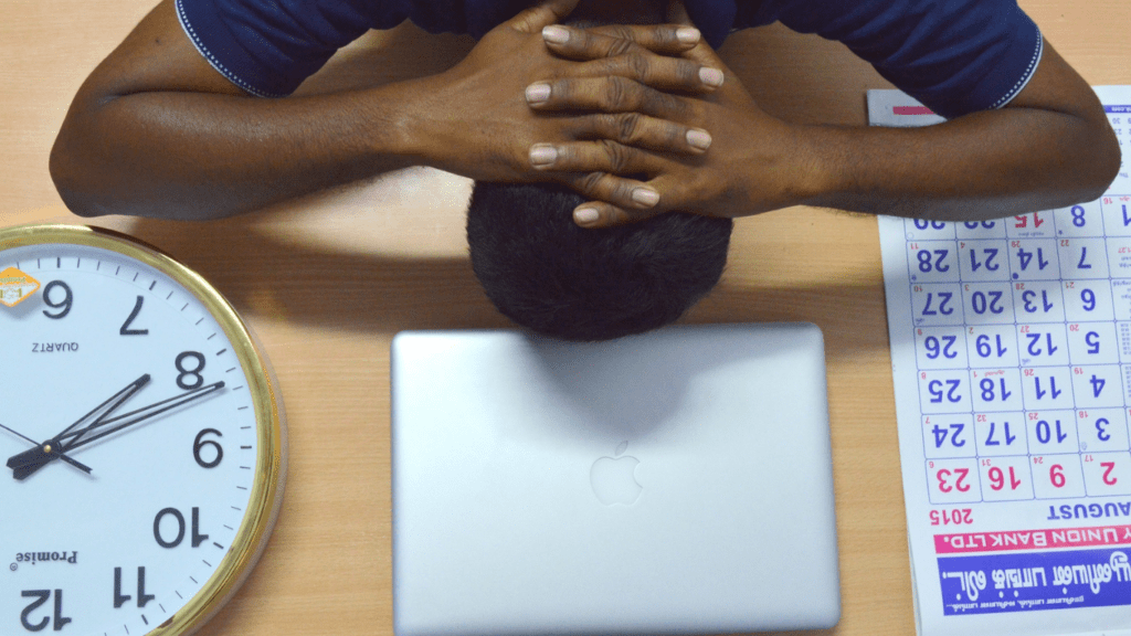 a person sitting at a desk with their head in their hands