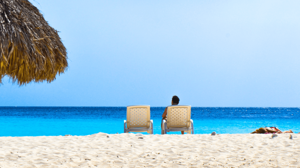 a person sitting on the beach looking up at the sky