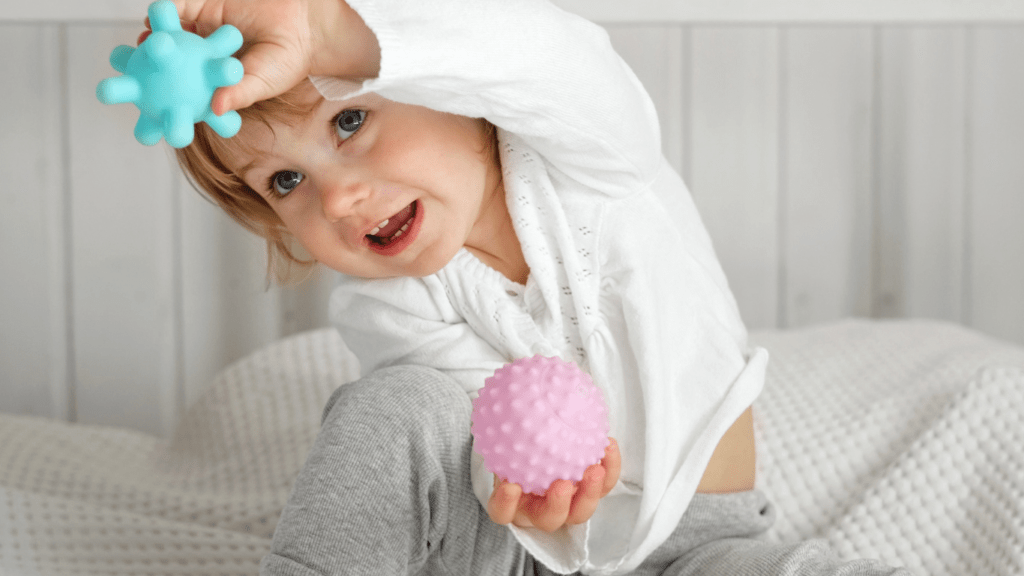 a toddler playing with toys on a bed