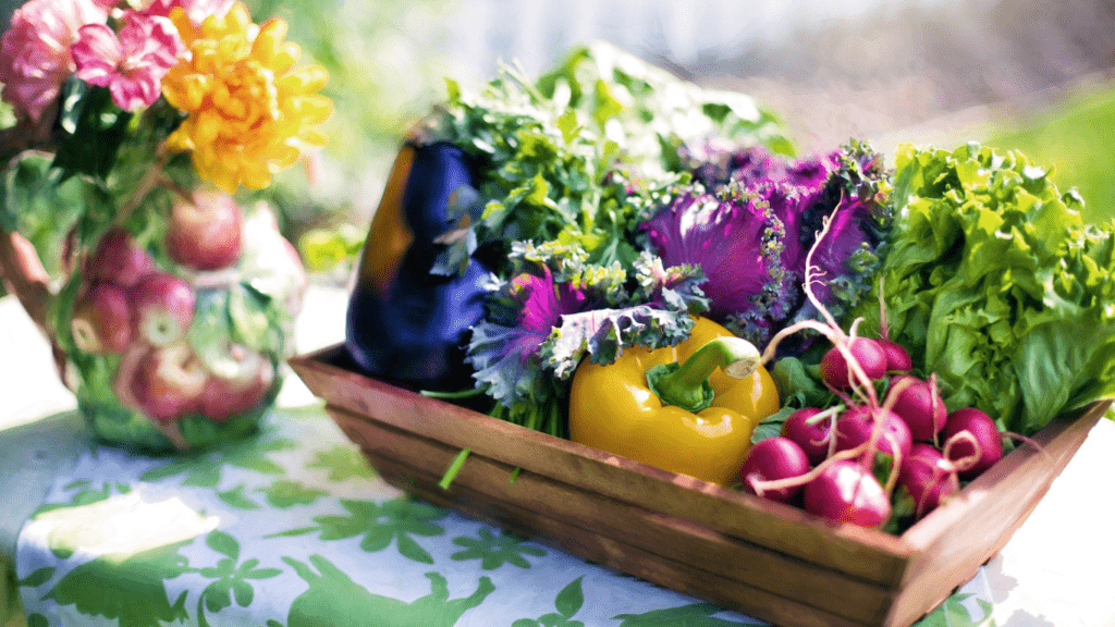 vegetables in a basket on a table with flowers in the background